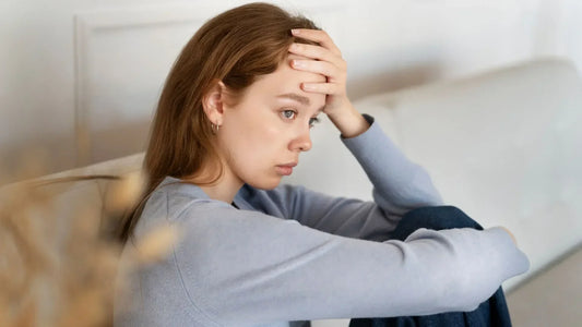 Femme assise dans son canapé anxieuse à cause du cortisol élevé