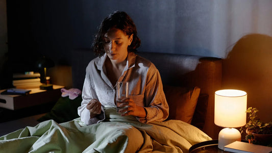 Femme dans son lit qui prend un médicament pour faire baisser son cortisol